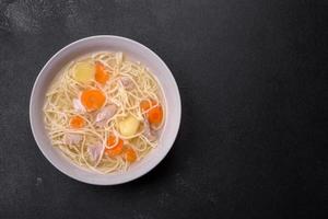 Delicious soup with noodles, chicken and carrots with spices and herbs photo