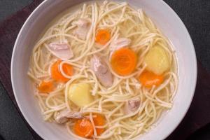 Delicious soup with noodles, chicken and carrots with spices and herbs photo
