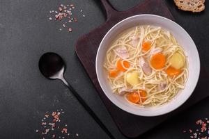 Delicious soup with noodles, chicken and carrots with spices and herbs photo