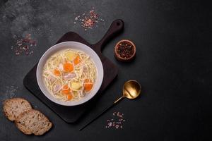 Delicious soup with noodles, chicken and carrots with spices and herbs photo