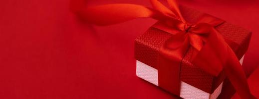 Gift box with festive ribbon on the red background. photo