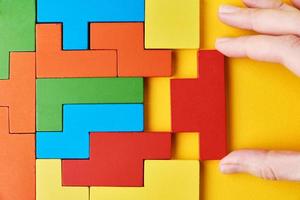 Woman hand adding last missing wooden block to finish puzzle photo