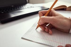 Woman makes notes in notebook and using laptop for study photo