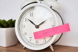 Sticky note with word later on white alarm clock photo