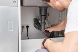 Male plumber repair sink pipe in kitchen photo