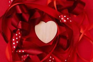 cinta festiva y corazón de madera sobre fondo rojo. día de San Valentín foto