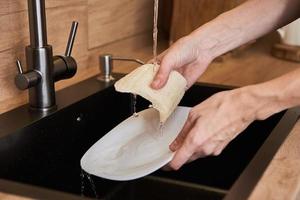 Woman wash dishes with organic eco friendly sponge. Zero waste concept photo