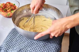 Woman in kitchen cooking a cake. Hands beat the dough with mixer