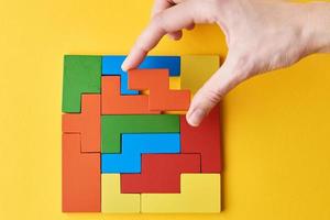 Woman hand adding last missing wooden block to finish puzzle photo