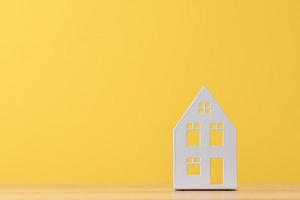 Figure of toy house on a yellow background with copy space photo