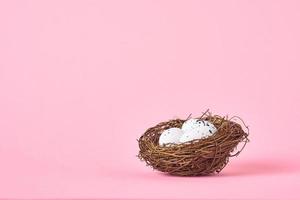 Nest with white eggs on the pink background with copy space photo