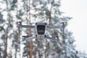 Drone quadcopter with camera flying in winter forest photo