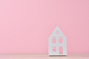 figura de casa de juguete sobre un fondo rosa con espacio de copia foto