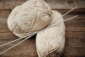 Two skeins of woolen yarn and needles for knitting on a wooden background photo