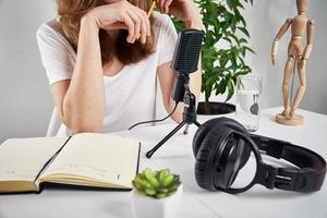 mujer grabando podcast en línea en casa. micrófono y auriculares en la mesa