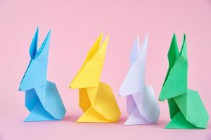 Paper colorful origami Esater rabbits on a pink background photo