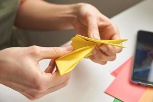 concepto de bricolaje. mujer hace origami conejo de pascua con papel de color. lecciones de origami foto