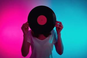 Woman hold retro vinyl disc with neon light photo