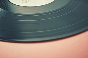 Old retro vinyl disc on a pink background. Vintage toned photo