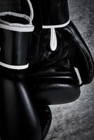 Pair of black boxing gloves on dark background, closeup photo