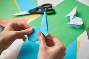 DIY concept. Woman make origami easter rabbit from color paper. Origami lessons photo