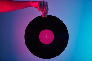 Hand hold retro vinyl disc with neon background photo