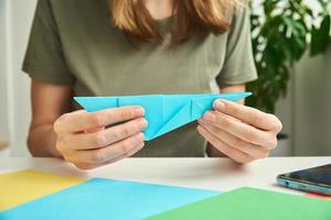 DIY concept. Woman make origami easter rabbit from color paper. Origami lessons photo