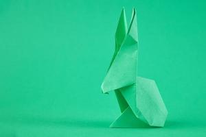 conejo de origami de papel sobre un fondo verde. concepto de celebración de pascua foto