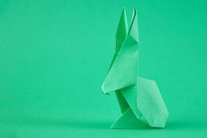 Paper origami Esater rabbit on a green background. Easter celebration concept photo