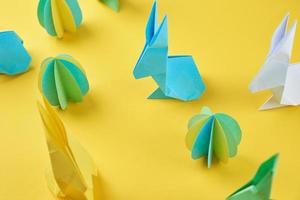 conejos de origami de papel y huevos de colores sobre fondo amarillo foto