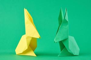 dos conejos eseter de origami de colores de papel en un verde. concepto de celebración de pascua foto