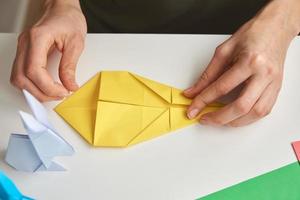 DIY concept. Woman make origami easter rabbit from color paper. Origami lessons photo
