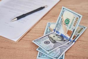 Document, pen and dollar bills on table, close up photo