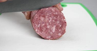 cutting sausage with a knife on a cutting board closeup video