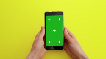 frau, die sich inhaltsvideos auf einem grünen mock-up-bildschirm mit chroma-key-smartphone ansieht video