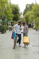 Portrait of cheerful Caucasian young couple man and woman holding many paper bags after shopping while walking and talking on street. Happy family couple with packages outdoor. Buying concept photo