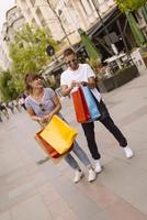 retrato de una alegre pareja joven caucásica hombre y mujer sosteniendo muchas bolsas de papel después de ir de compras mientras camina y habla en la calle. feliz pareja familiar con paquetes al aire libre. concepto de compra foto