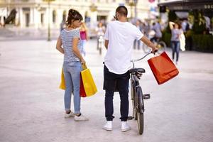 Portrait of cheerful Caucasian young couple man and woman holding many paper bags after shopping while walking and talking on street. Happy family couple with packages outdoor. Buying concept photo