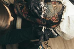 máquina de tatuaje de cerca. mujer creando una imagen a mano con ella en el salón foto