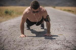 Male athlete exercising push up outside in sunny sunshine. Fit shirtless male fitness model in crossfit exercise outdoors. Healthy lifestyle concept. photo
