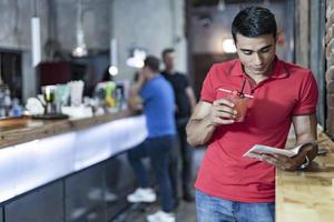 Handsome young man reading book at bar counter. photo