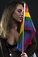 mujer lesbiana sosteniendo la bandera del arco iris aislada sobre fondo negro. símbolo internacional lgbt de la comunidad lesbiana, gay, bisexual y transgénero. foto