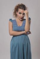 bella mujer con vestido azul posando en el estudio con fondo gris foto
