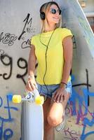 hermosa chica hipster con patineta con gafas de sol en la ciudad. foto