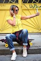Beautiful hipster girl with skate board wearing sunglasses in the city. photo