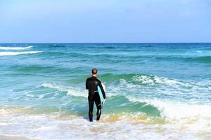 un hombre está de pie con un oleaje en sus manos en la orilla del mar. foto