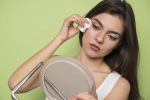 Close up beauty portrait of a young attractive woman cleaning her face with a cotton pad photo