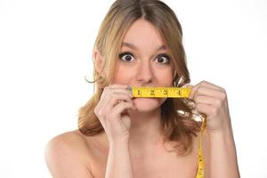 Portrait of beautiful woman with blond hair holding metering tape on white background photo