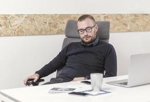 Young business man working at home with laptop and papers on desk photo