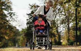 Grandmother and her autistic grand daughter enjoying holiday together outdoors, lying on green grass on blanket and smiling to camera. Leisure family lifestyle, happiness and moments. photo